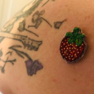 Embroidered strawberry next to the edge of a tattoo